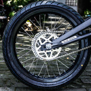 Close-up of a motorcycle wheel with chain and 'Sur-Ron' brand name.